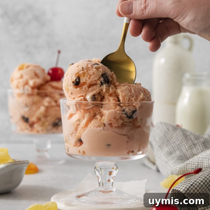 a hand holding a gold toned spoon in a dish of homemade tutti frutti ice cream
