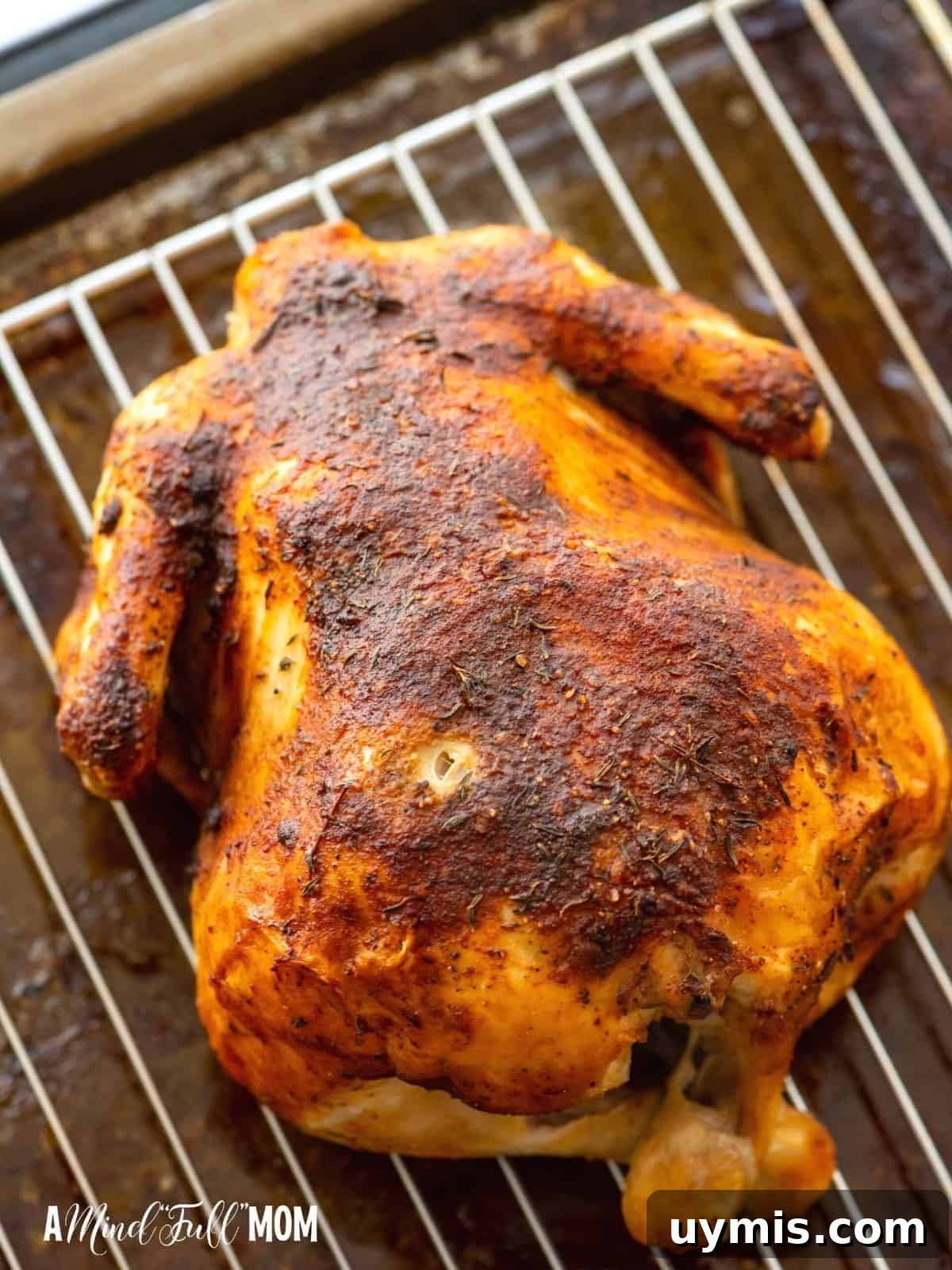Homemade baked rotisserie chicken on a baking rack.