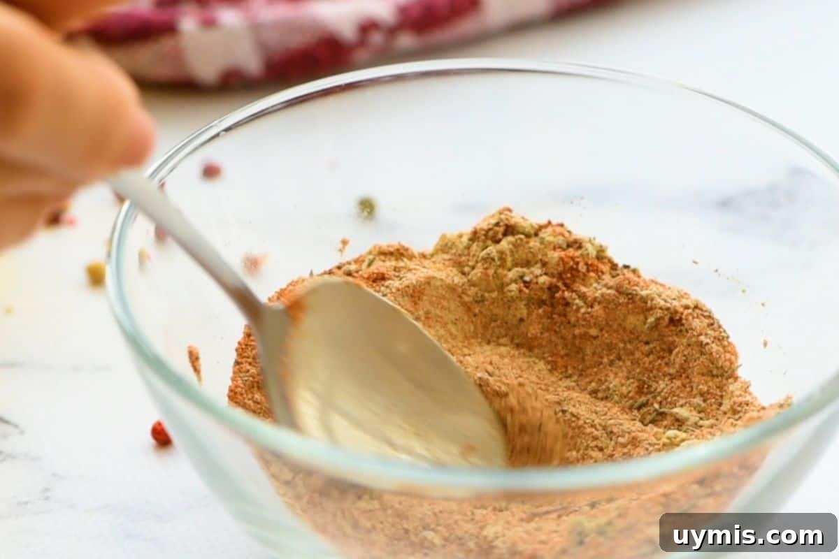 Salt, pepper, onion powder, garlic powder, paprika, thyme, and cayenne being mixed in a small bowl.