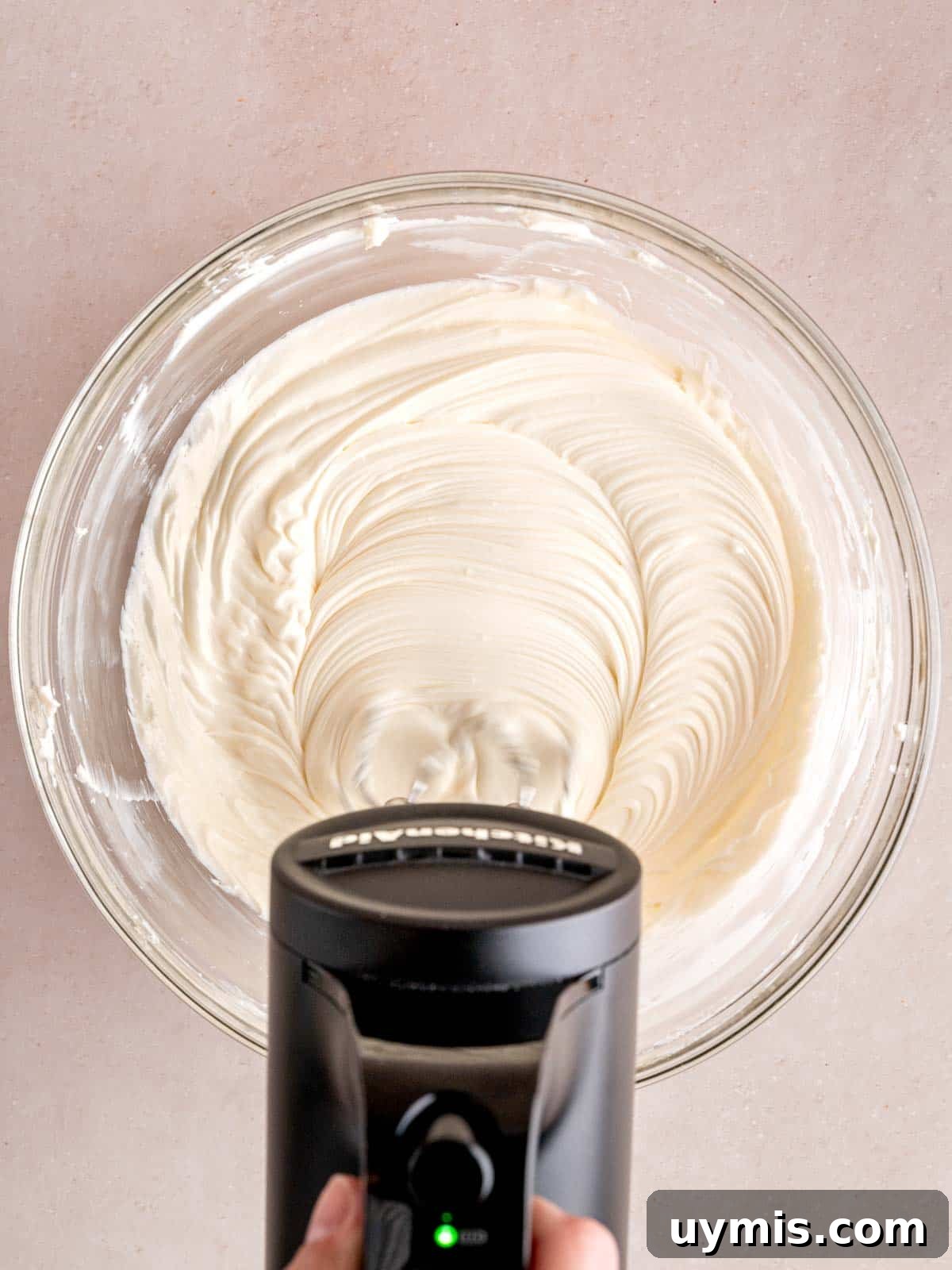 Creamy No-Bake Chocolate Cherry Cheesecake Recipe 9 Mixing cream cheese with sugar and lemon juice in a bowl with a cordless KitchenAid hand mixer.