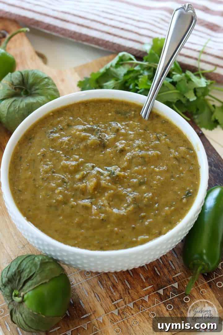 A white bowl full of tomatillo enchilada sauce sitting on a wooden board.