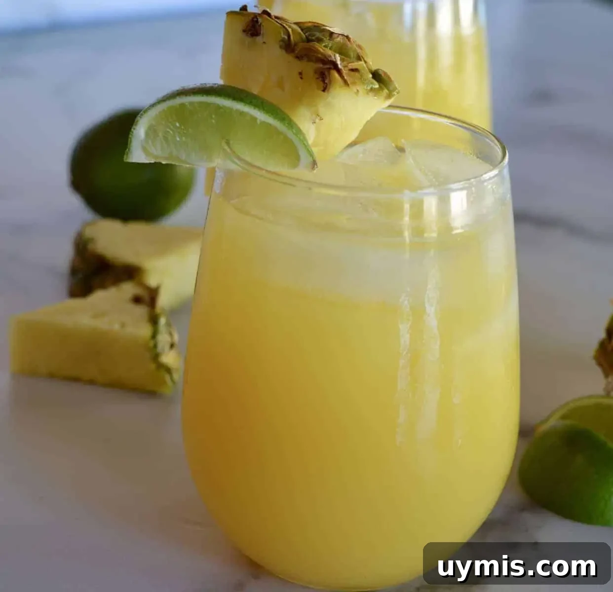 How to Make a Pineapple Margarita Cocktail 3 Glass of pineapple margarita with a lime and pineapple garnish.