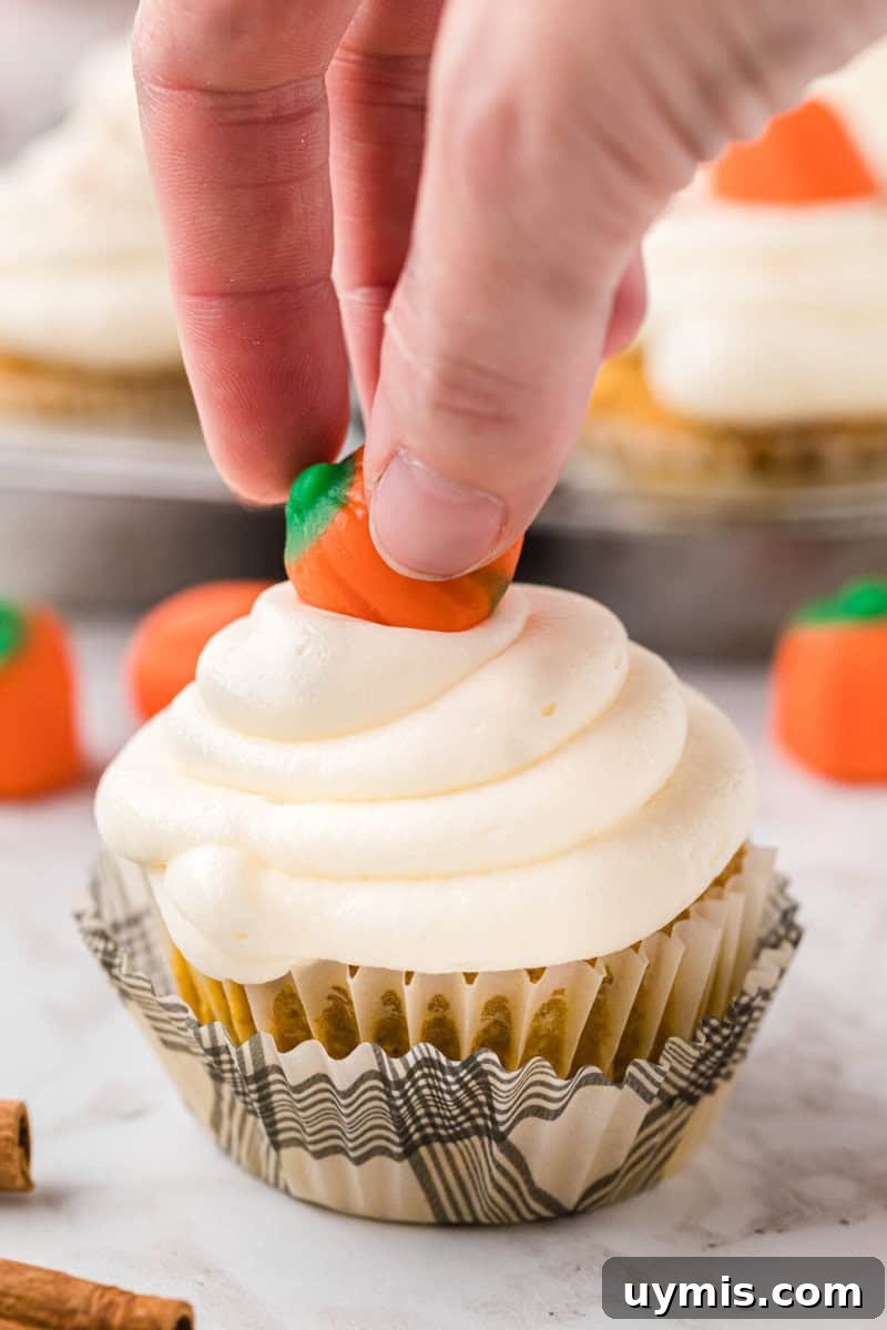 Moist Pumpkin Cupcakes with Cinnamon Cream Cheese Frosting 13 topping the cupcake with a candy pumpkin.
