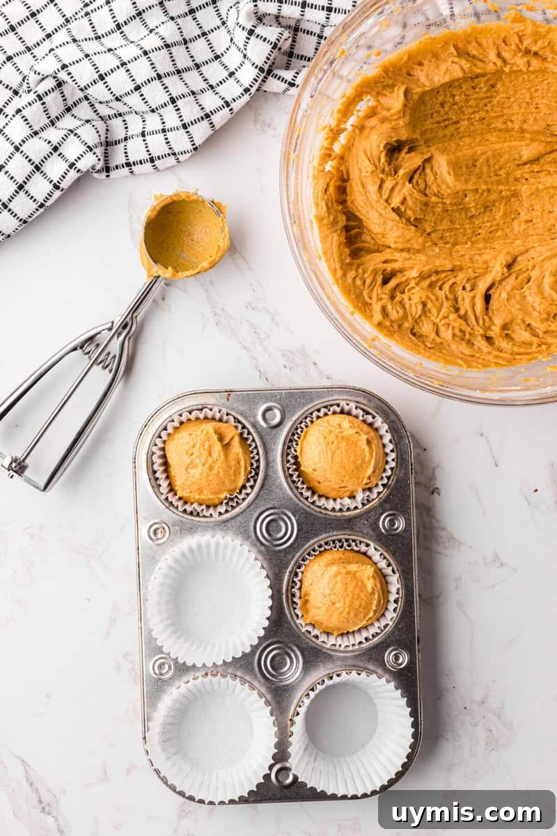 Moist Pumpkin Cupcakes with Cinnamon Cream Cheese Frosting 9 filling the cupcake liners with the batter in the cupcake pan.