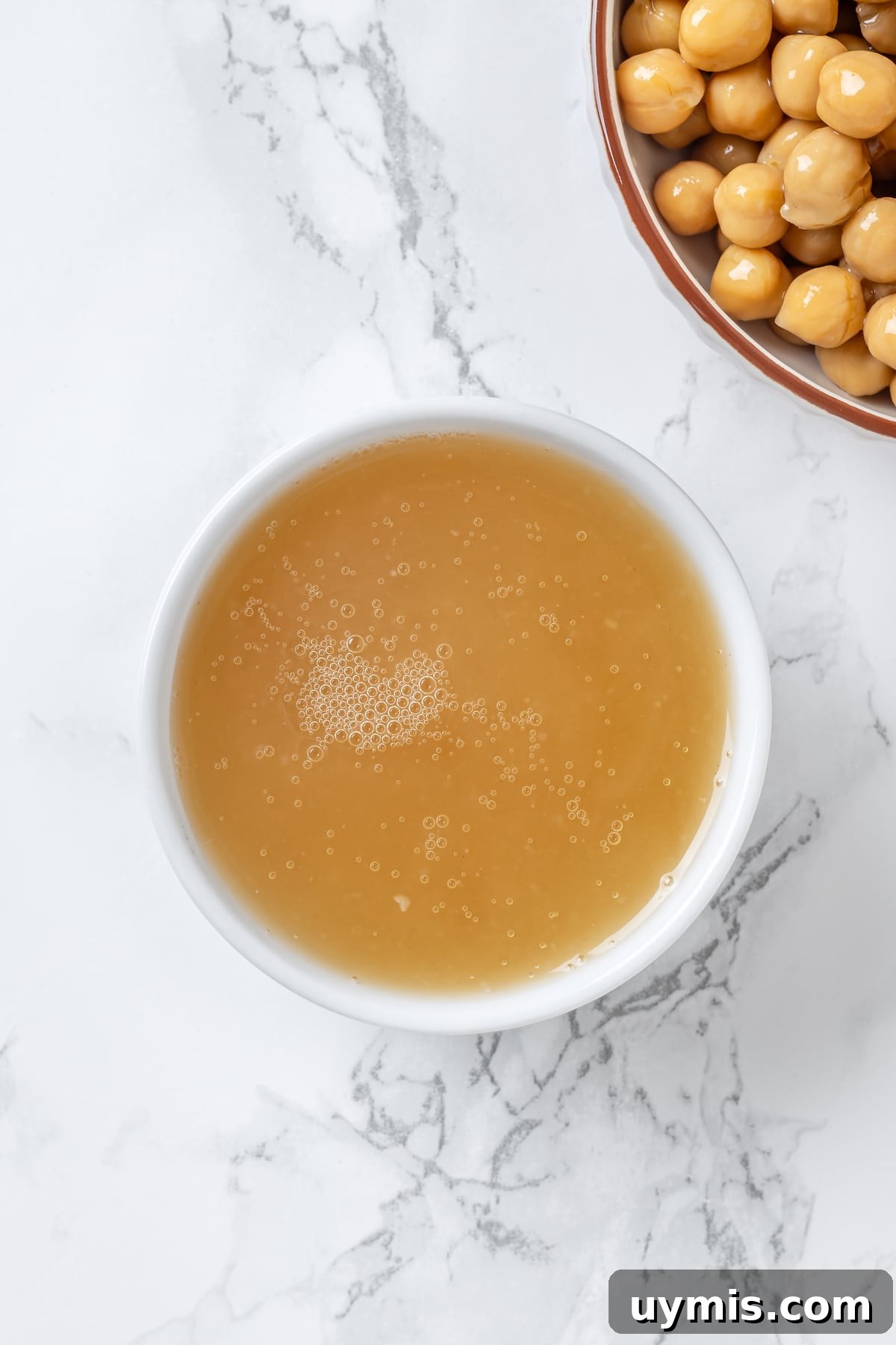 Aquafaba is a miracle worker in vegan baking. But what is aquafaba? And how do you use it? Here’s everything you need to know! Overhead view of chickpea liquid in small white bowl