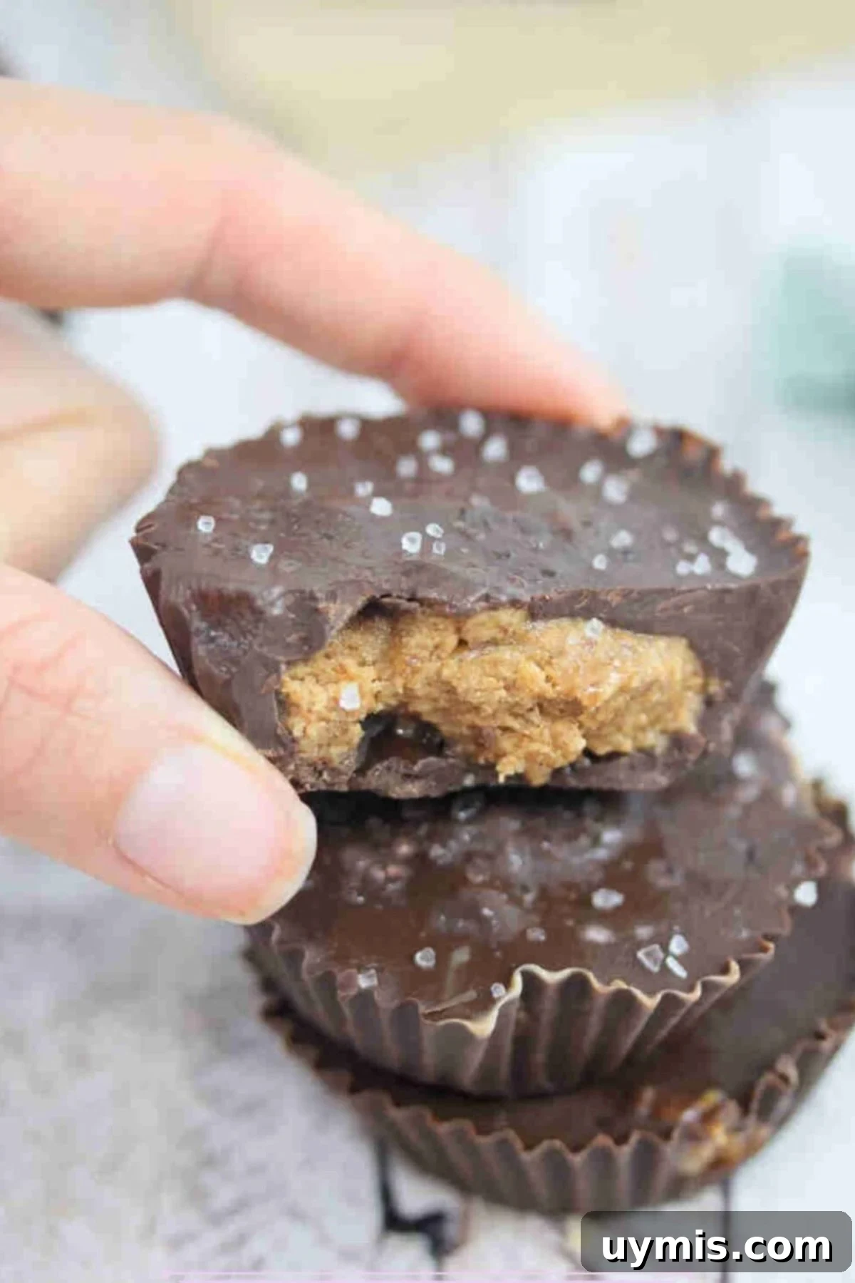 High-Protein Almond Butter Dark Chocolate Cups 2 Fingers holding a chocolate almond butter protein cup on top of another.