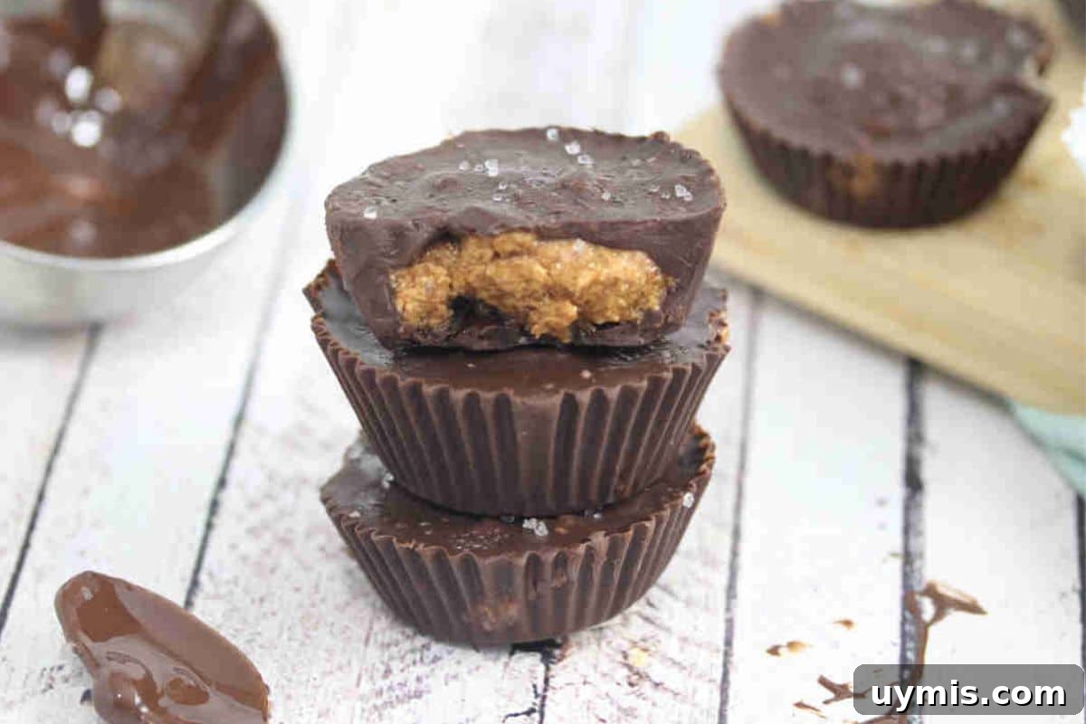 Three almond butter protein cups stacked with the top having a bite out of it.