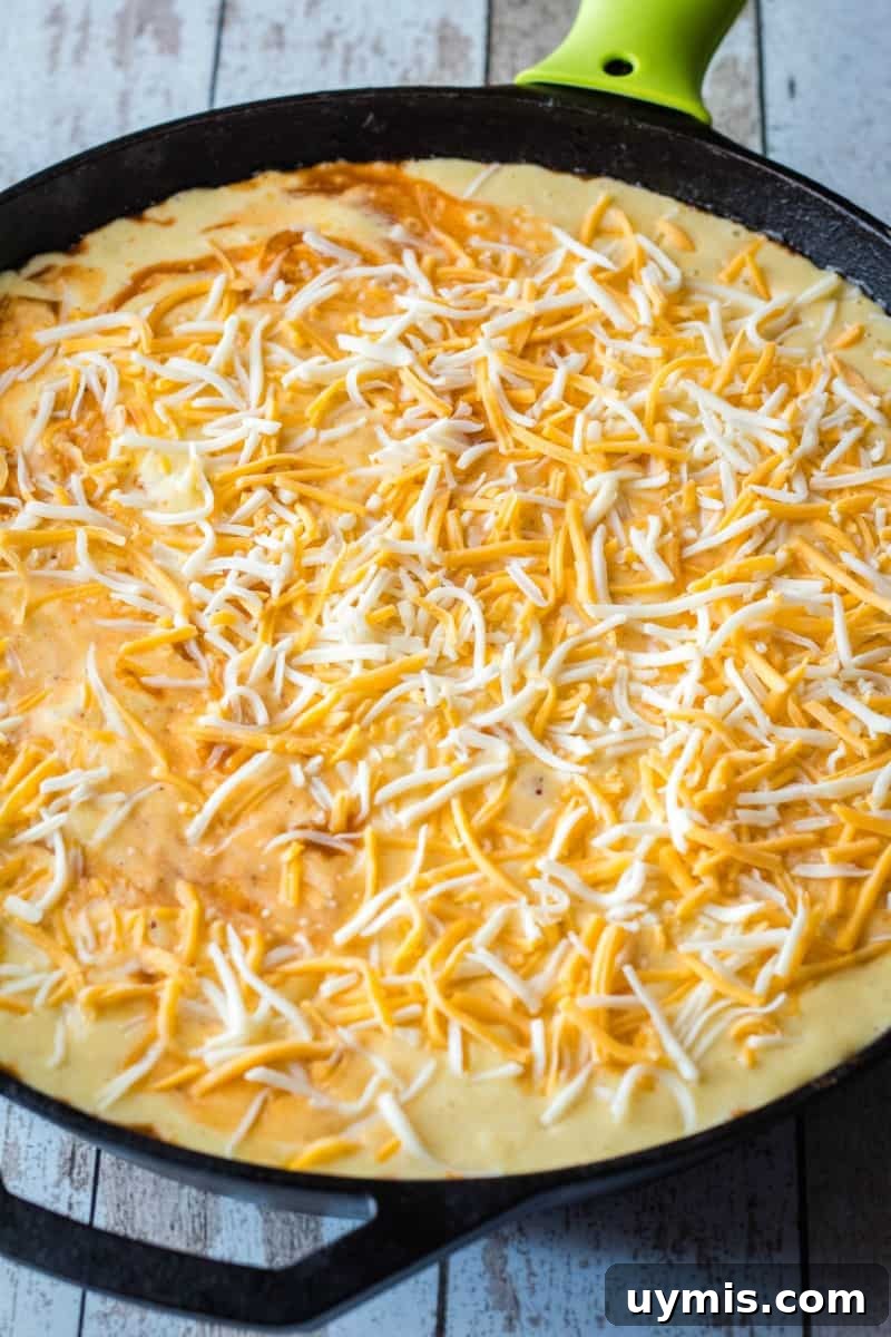 cornbread batter and cheese on top of sloppy joe skillet before baking