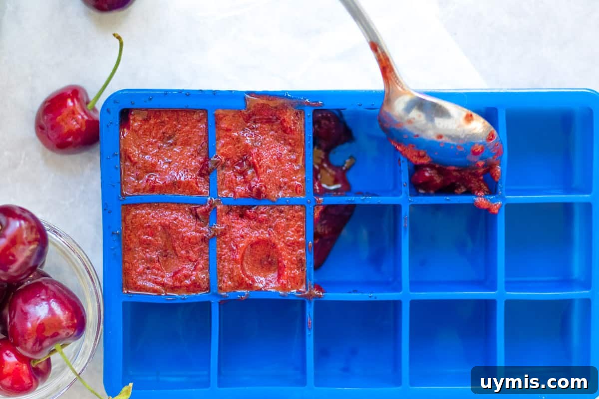 spooning cherry puree into an ice cube tray
