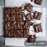 Chocolate Brownies with Port-Soaked Cherries 7 Top view of cut squares of brownies on white parchment paper on a grey stone background