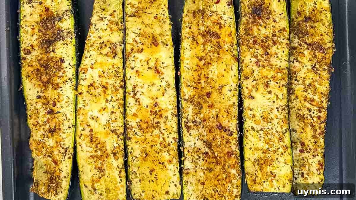 How to Smoke Zucchini on a Pellet Grill 2 Smoked zucchini slices arranged neatly on a baking sheet, showcasing their perfectly charred edges and vibrant green color, ready to be served.