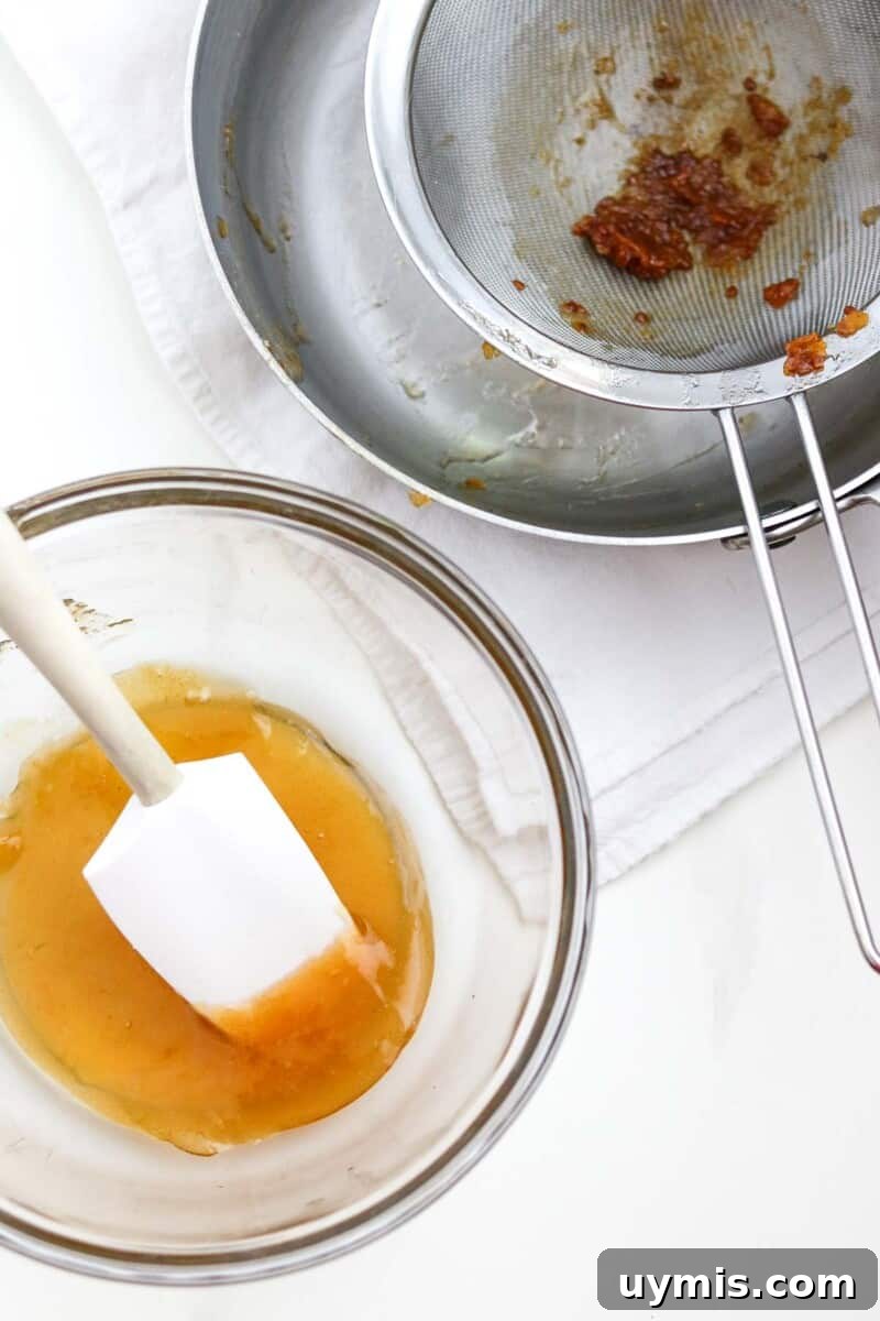 Multekrem: Norwegian Cloudberry Cream Recipe 5 Strained cloudberry preserves in a glass bowl next to a strainer.