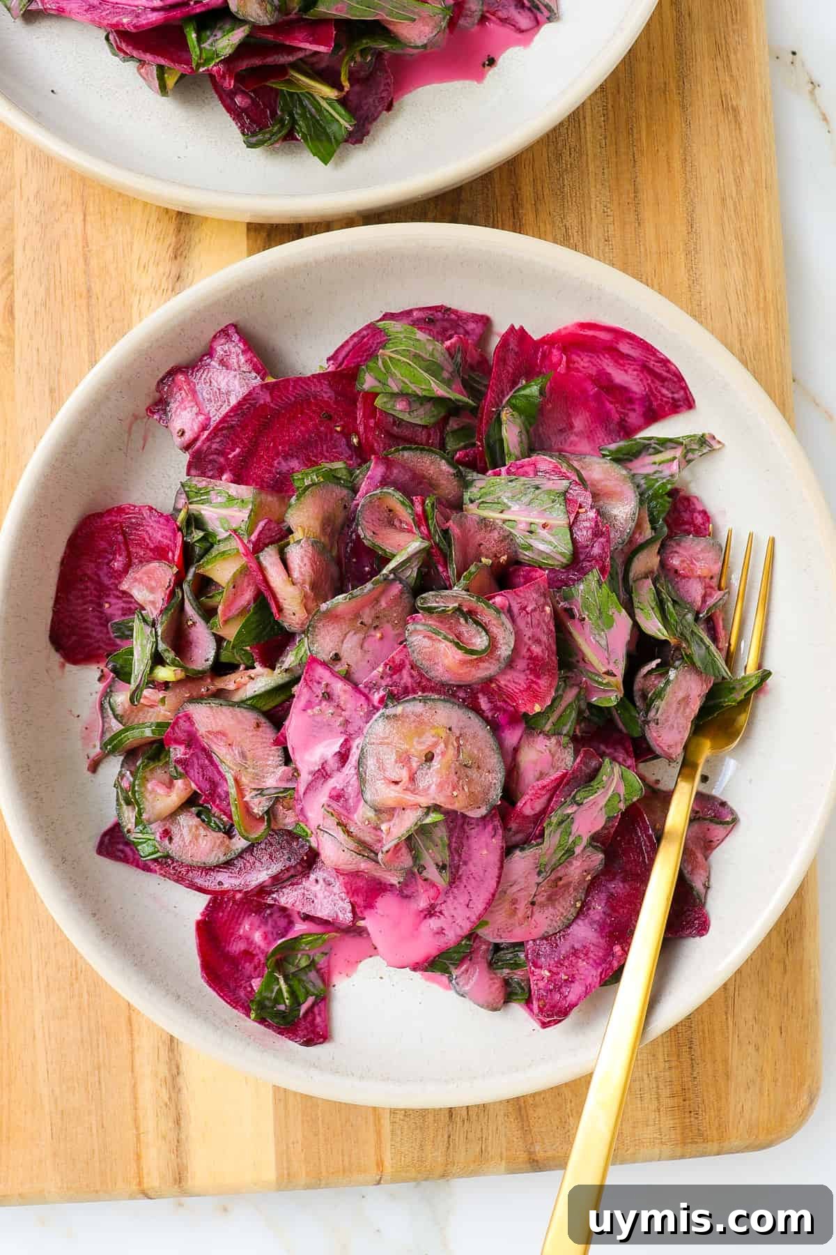 Cucumber and Beetroot Salad Recipe 2 Cucumber beetroot salad in a bowl on a wooden board.