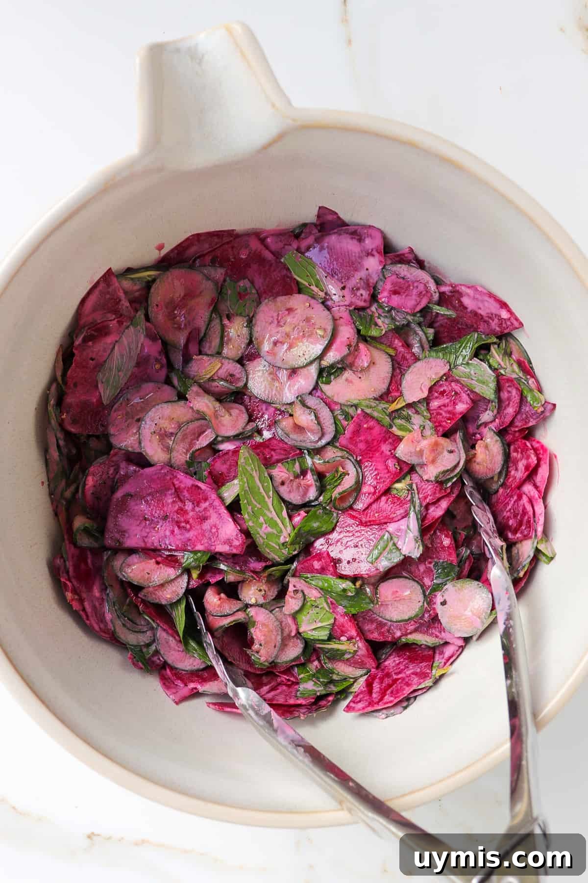 Cucumber and Beetroot Salad Recipe 7 Cucumber beetroot salad in a mixing bowl with metal tongs.