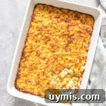 Creamy Scalloped Corn Casserole Recipe 11 the cooked scalloped corn casserole inside a baking dish with a spoon removing a portion