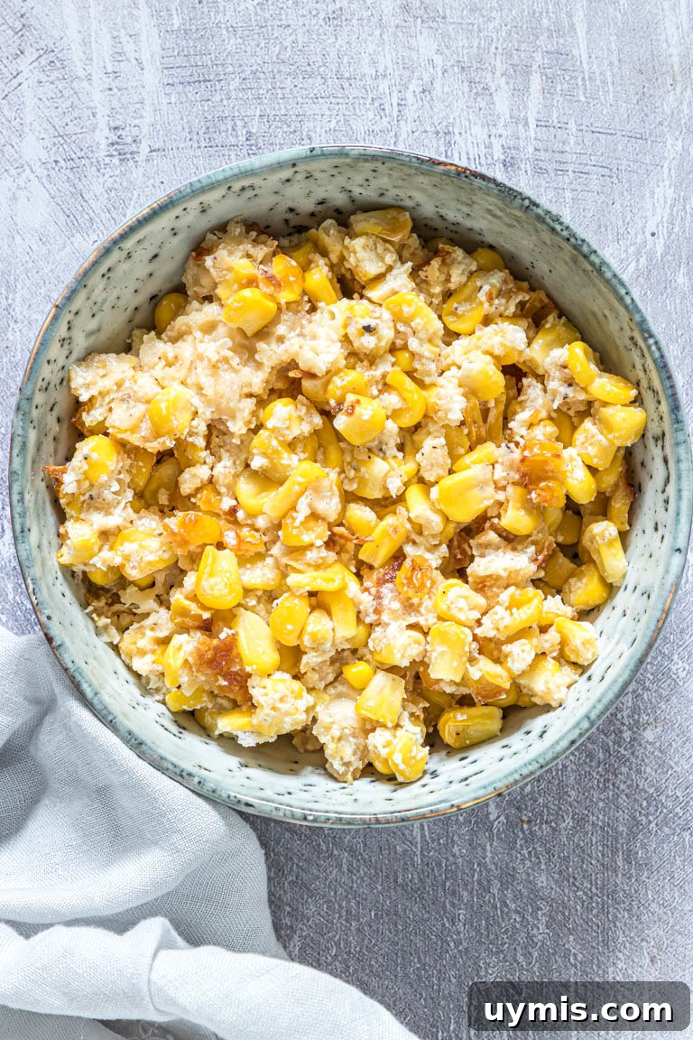 Creamy Scalloped Corn Casserole Recipe 5 the finished scalloped corn served on a blue ceramic bowl with a cloth napkin