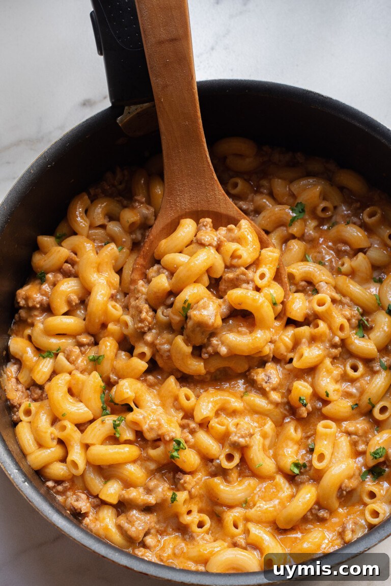 Creamy Scalloped Corn Casserole Recipe 9 a wooden spoon removing one portion from the hamburger pasta in the skillet