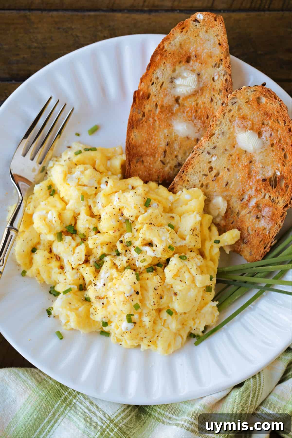 scrambled eggs on a plate with toast and a fork on the side