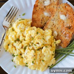 scrambled eggs on a plate with toast and a fork on the side