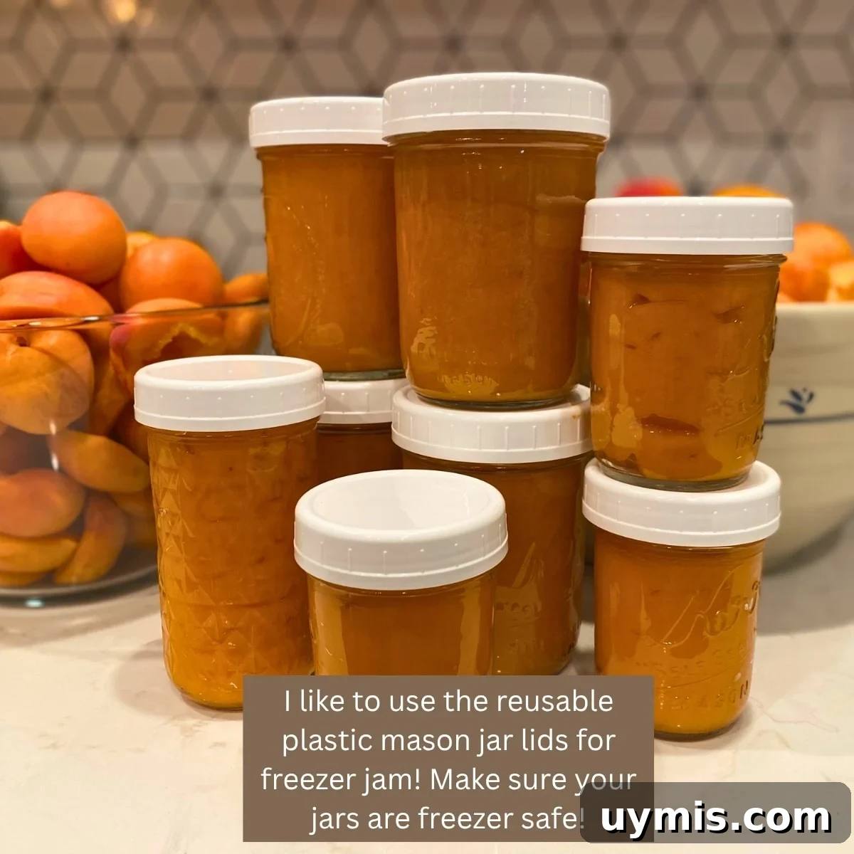 Low Sugar Apricot Freezer Jam Recipe Without Pectin 3 Homemade apricot freezer jam in a glass mason jars stacked on the counter with a bowl of fresh apricots behind them.