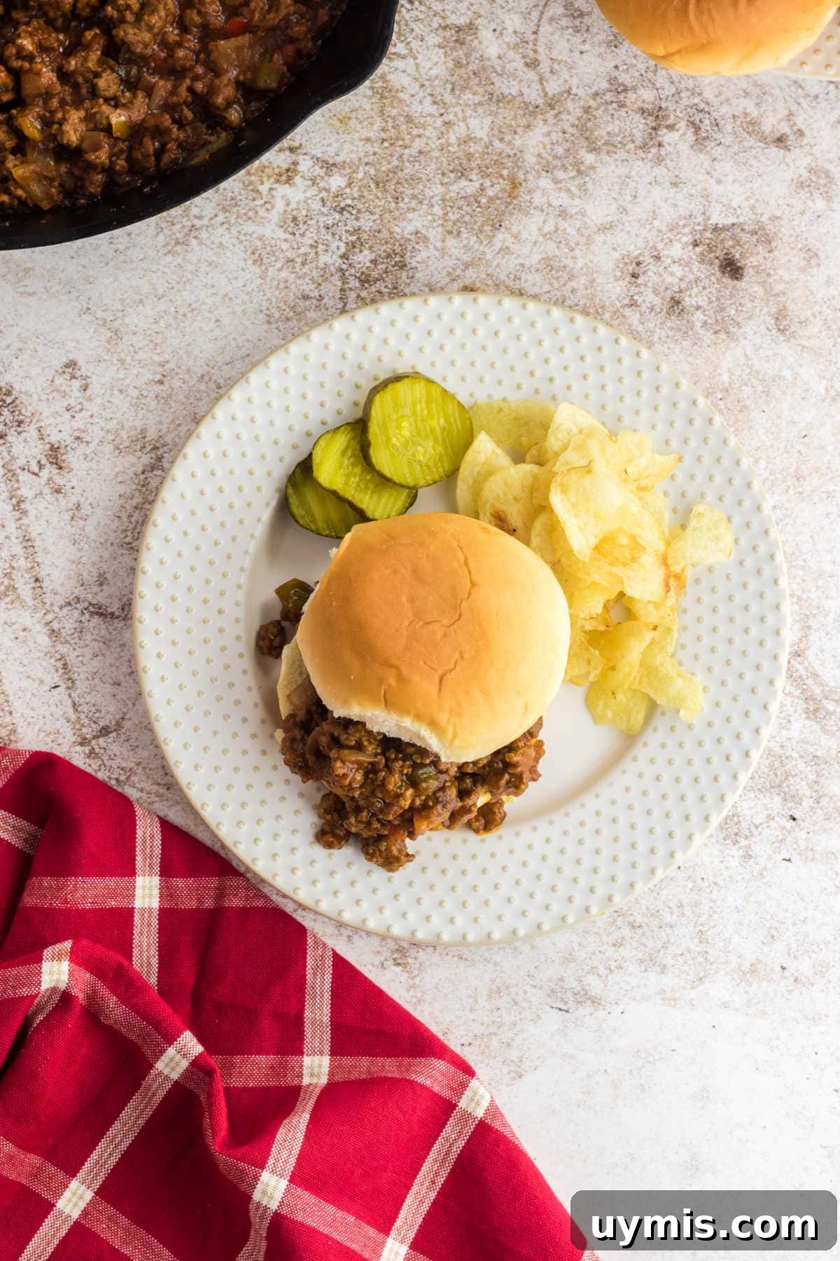 Old Fashioned Sloppy Joes Recipe 5 Overhead view of a sloppy joe sandwich on a plate with pickles.