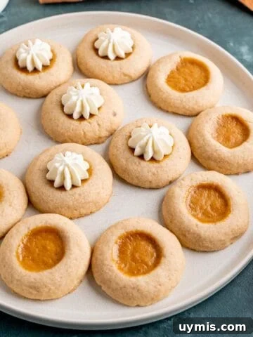 A plate of pumpkin pie filled thumbprint cookies with whipped cream.