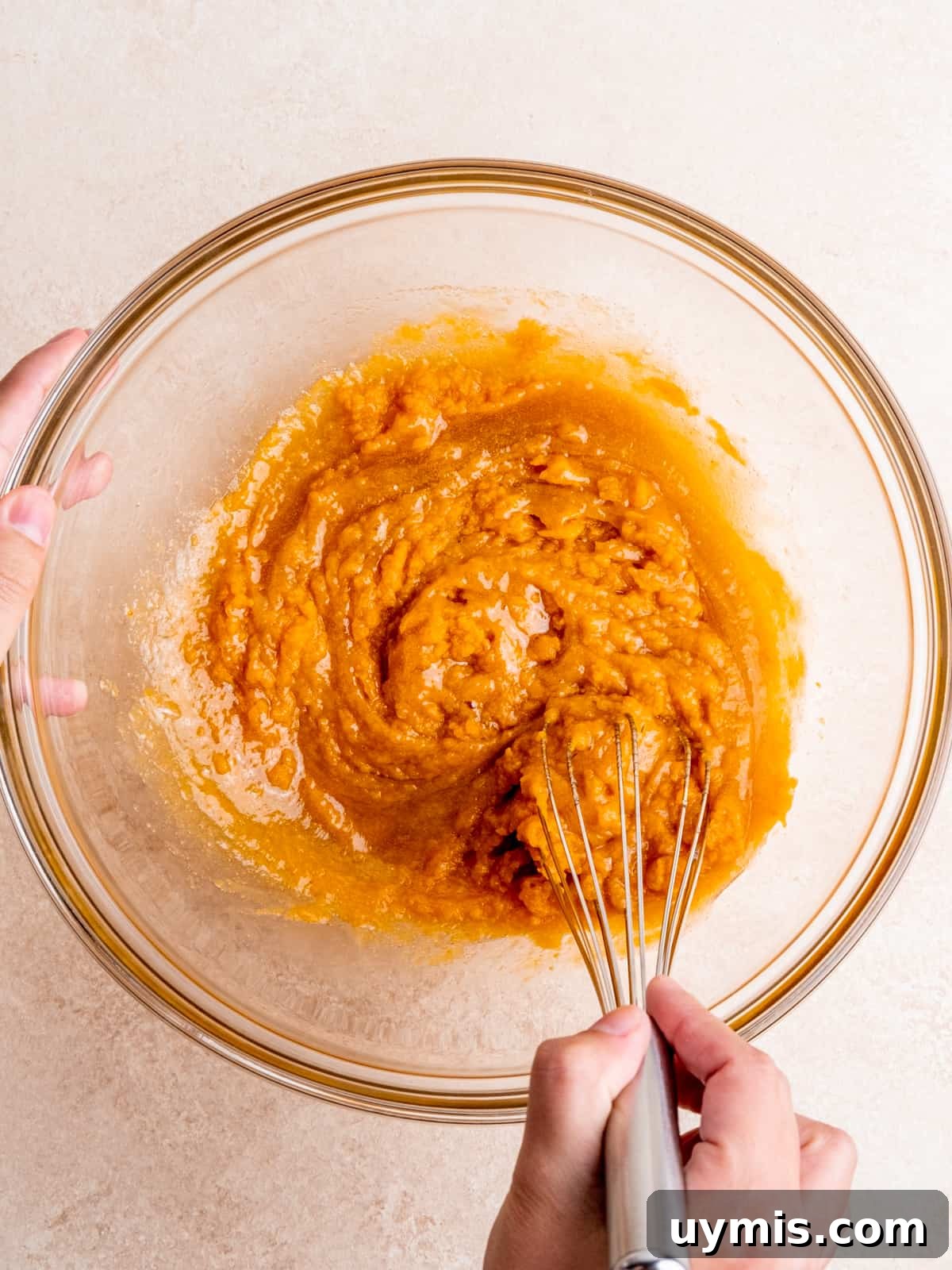 Whisking oil, sugars, egg, vanilla extract and pumpkin puree in a bowl.