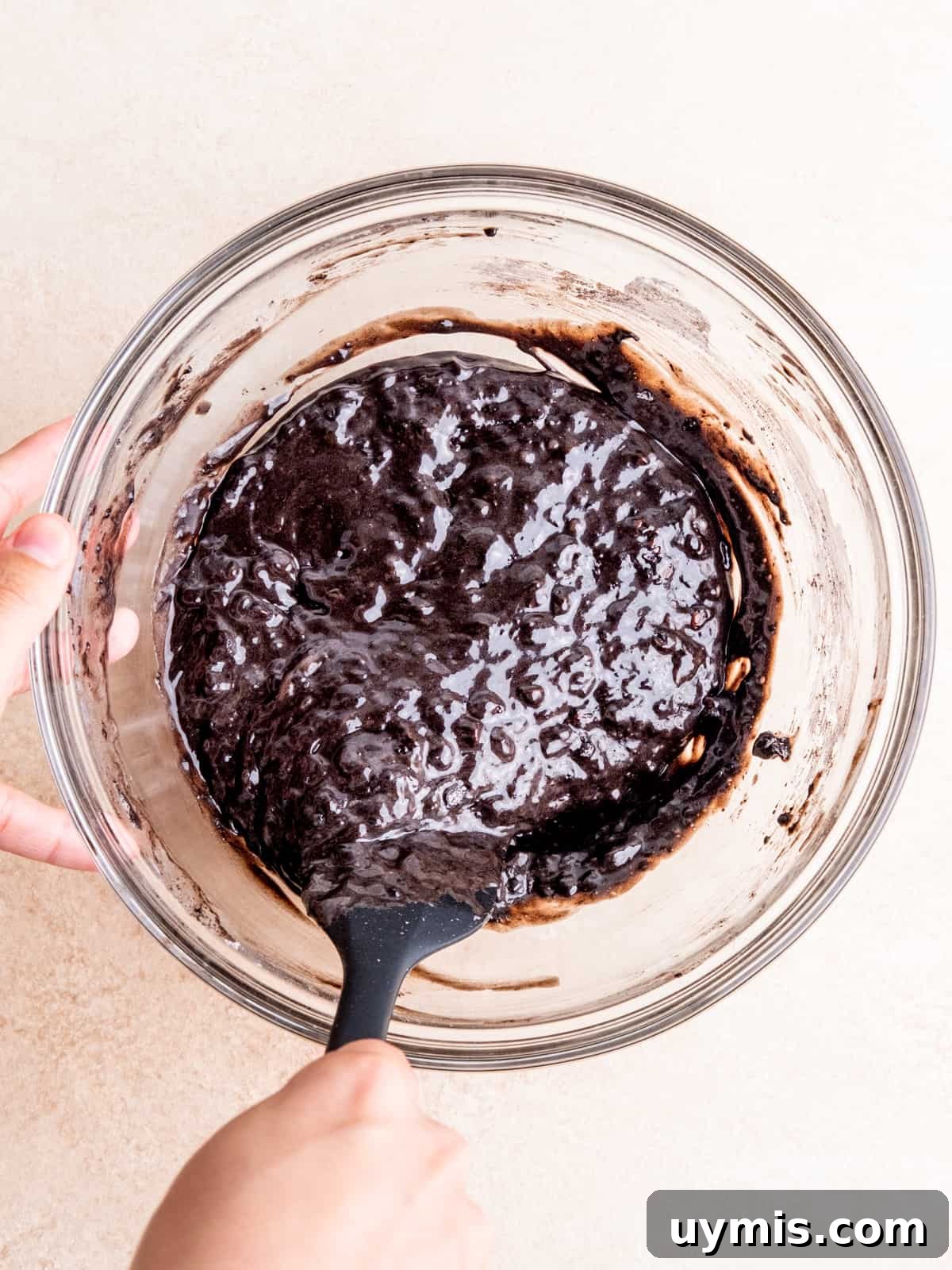Folding double chocolate muffin batter in a bowl with a spatula.