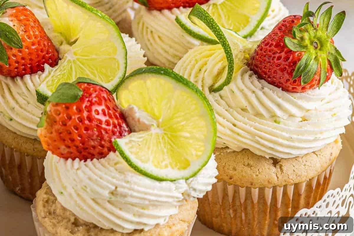 Labor Day Dessert Recipes for Summer Cookouts 6 strawberry margarita cupcakes on a cake stand topped with fresh strawberries and lime wheels.