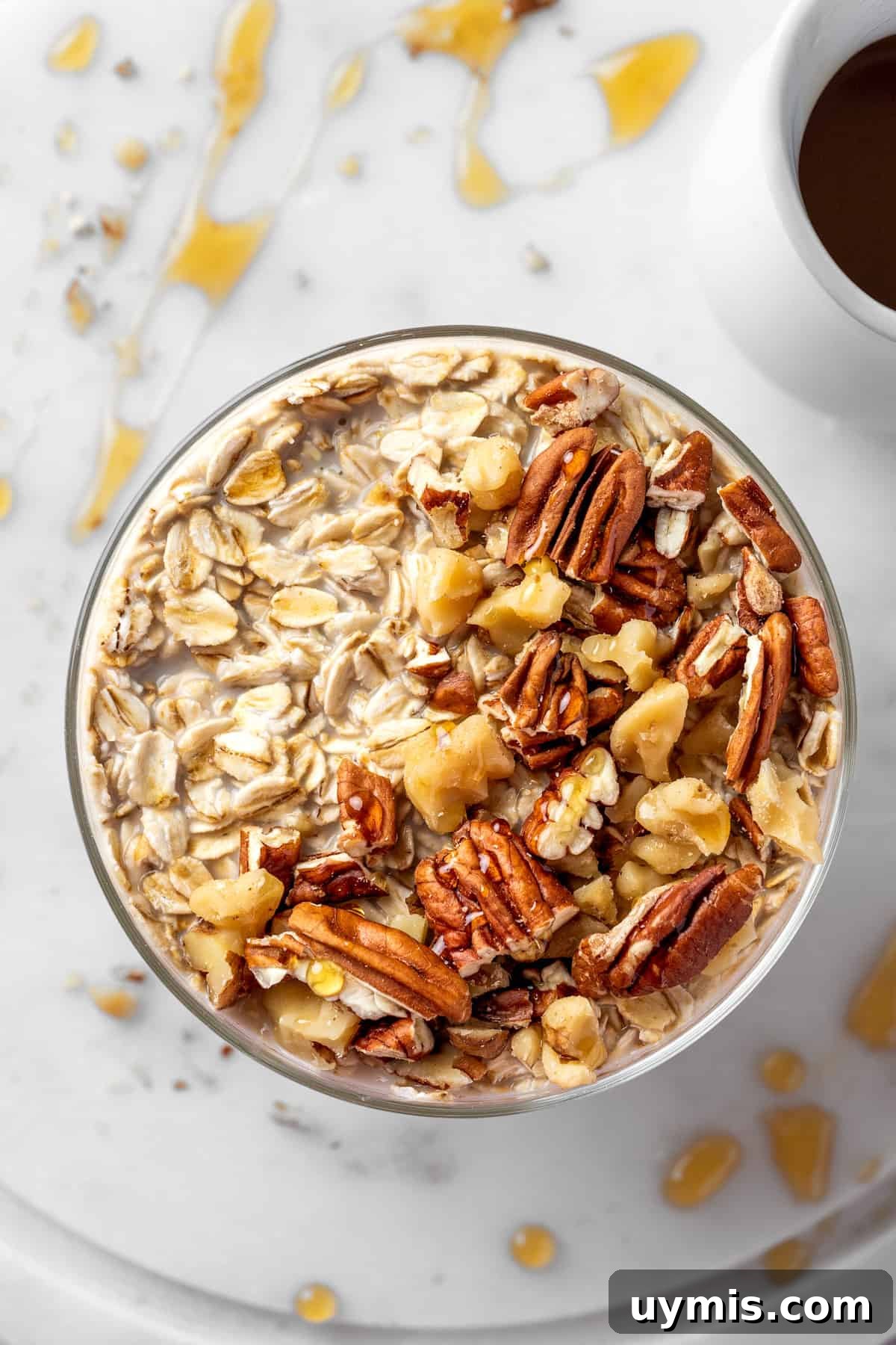 A bowl of maple brown sugar overnight oats topped with toasted nuts and a drizzle of maple syrup.