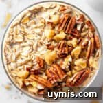A bowl of maple brown sugar overnight oats topped with toasted nuts and a drizzle of maple syrup.