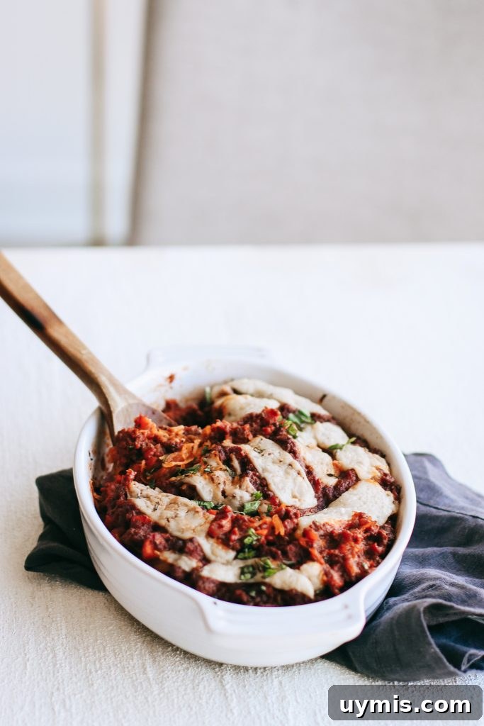 Spaghetti squash bake in a white dish with a wooden spoon and a dish towel