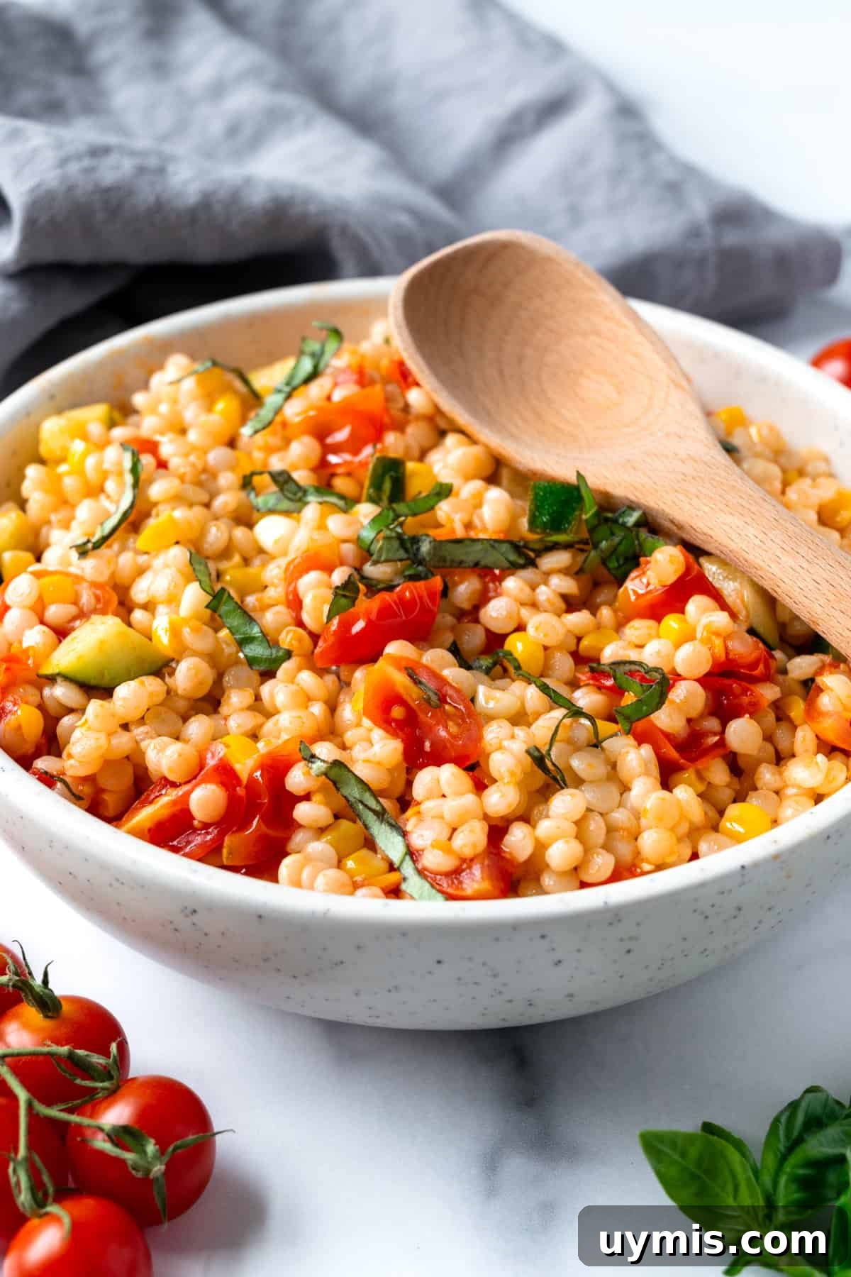 Zesty Summer Couscous Salad with Fresh Herbs 2 Pearl Couscous Salad in a white bowl with a spoon.