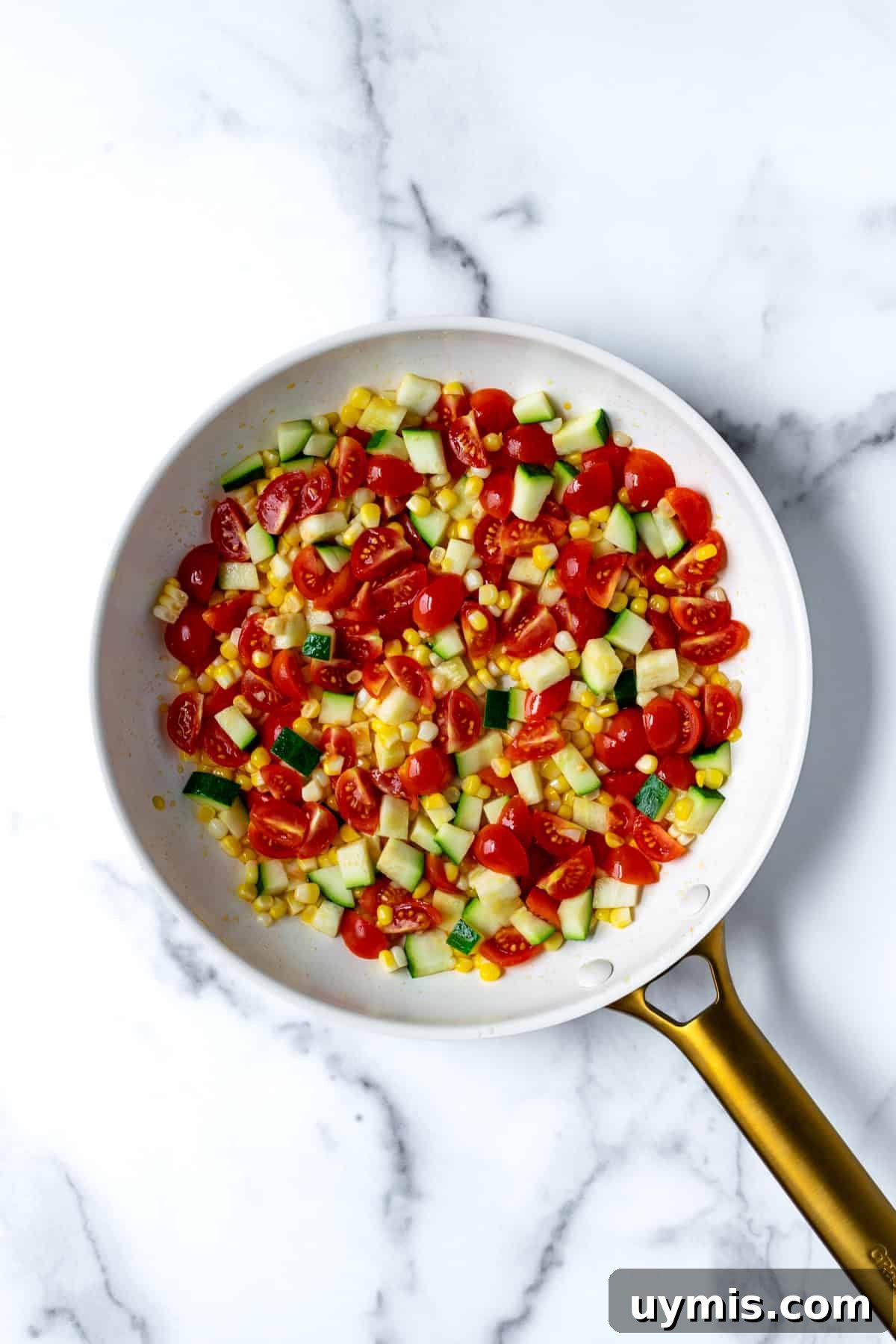 Zesty Summer Couscous Salad with Fresh Herbs 5 Sauteed summer veggies in a white skillet.