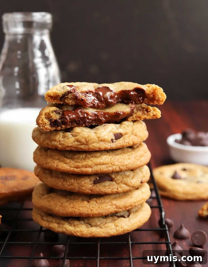 No-Chill Chocolate Chip Cookie Recipe 12 stack of best brown butter chocolate chip cookies on cooling rack with cookie split in half showing gooey insides