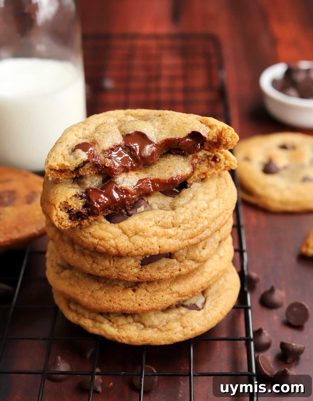 No-Chill Chocolate Chip Cookie Recipe 8 stack of best brown butter chocolate chip cookies on cooling rack with cookie split in half showing gooey insides