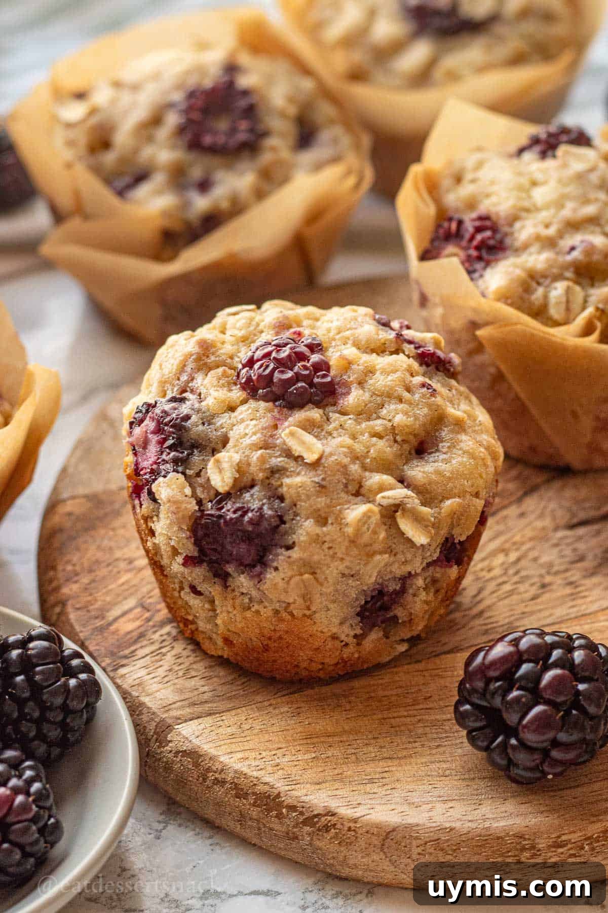 Banana Blackberry Oatmeal Muffins with Rolled Oats 2 Baked banana blackberry oatmeal muffin on wood cutting board with blackberries.