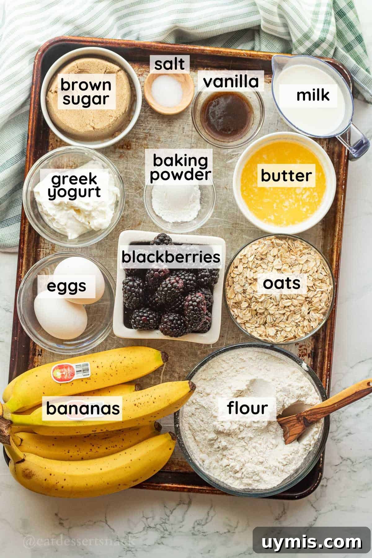 Banana Blackberry Oatmeal Muffins with Rolled Oats 3 Labeled ingredients for banana blackberry oat muffins on metal baking sheet.