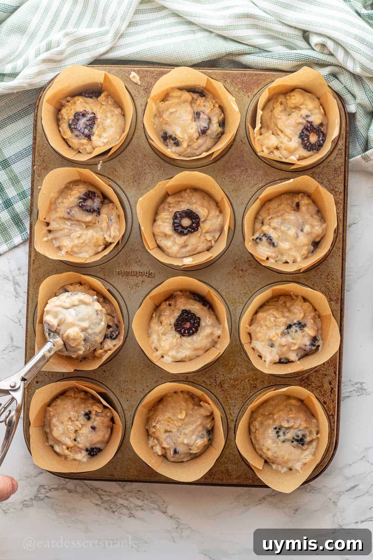 Banana Blackberry Oatmeal Muffins with Rolled Oats 9 Scooping raw banana blackberry oat muffin batter into muffin tin.