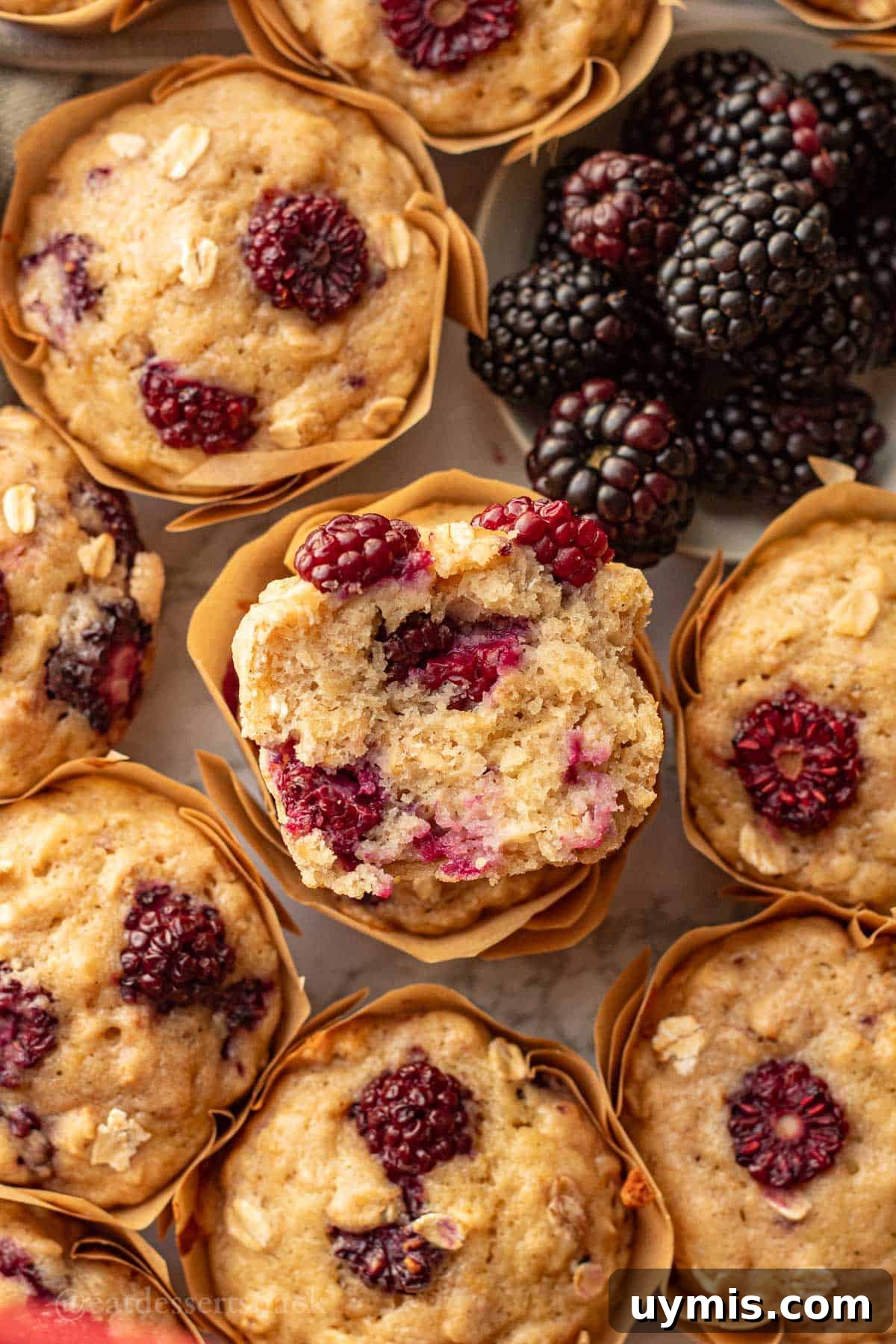 Banana Blackberry Oatmeal Muffins with Rolled Oats 10 Half of a blackberry banana oatmeal muffin stacked on another baked muffin.