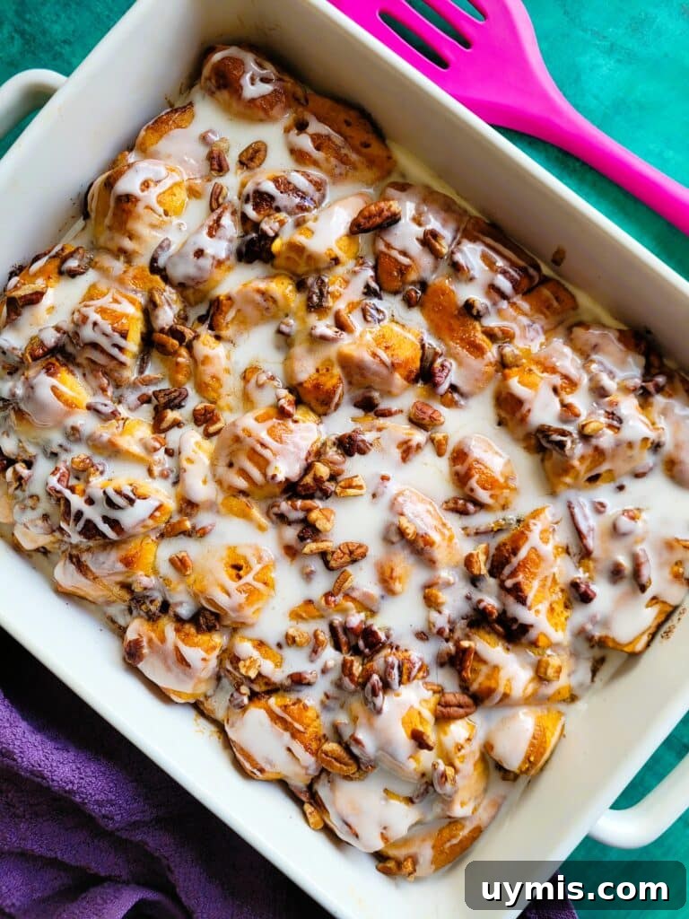 Overhead shot of the baked cinnamon roll breakfast casserole, maple syrup and icing drizzled, ready for serving at a holiday brunch table.