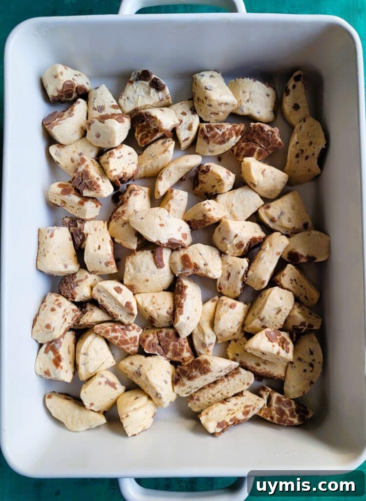 Cutting canned cinnamon rolls into quarters using kitchen scissors for the breakfast casserole.