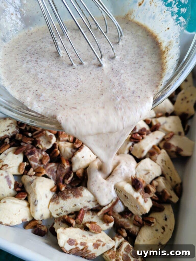 Pouring custard evenly over cinnamon roll pieces in a greased 9×13-inch baking dish.