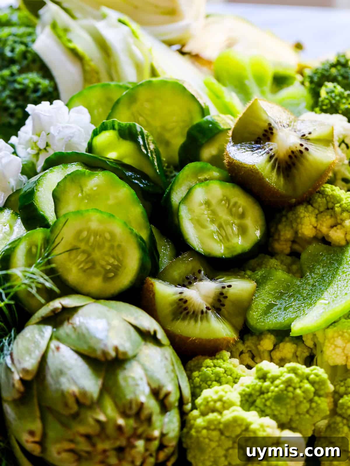 St. Patrick's Day Green Snack Ideas for Parties 7 A pile of green vegetables on a tray with slices of cucumber, kiwi, artichokes and more.