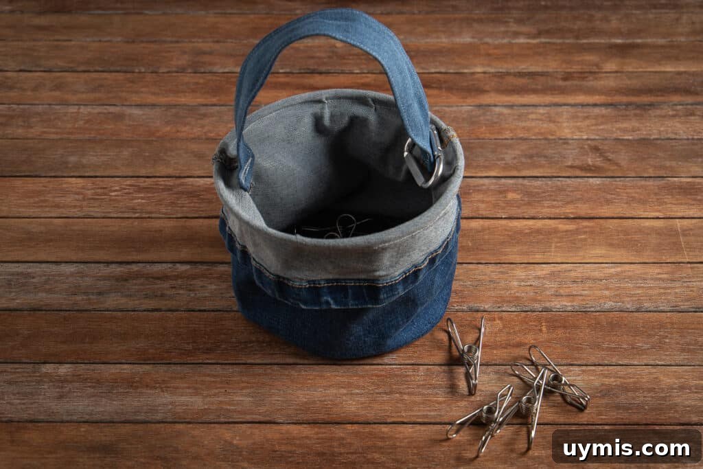 Upcycled denim peg bag from old jeans on a wooden background with pegs scattered at the front