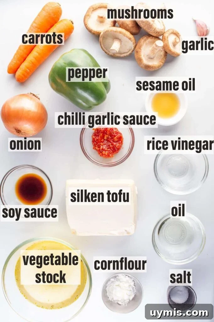 Quick Spicy Silken Tofu Recipe with Garlic Chili Sauce 3 Labelled ingredients including carrots, mushrooms, garlic, pepper, onion, chilli garlic sauce,sesame oil, rice vinegar, soy sauce, silken tofu, oil, salt, cornflour and vegetable stock.