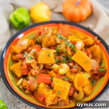 A colorful bowl of seasoned, cooked vegetables featuring Caribbean pumpkin, squash, carrots, bell peppers, and onions, garnished with chopped herbs.