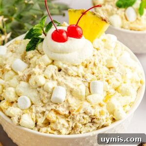 Pina colada fluff salad topped with extra marshmallows, Cool Whip, cherries, and a pineapple wedge.