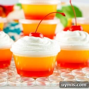 tequila sunrise jello shots with whipped cream and a cherry on top