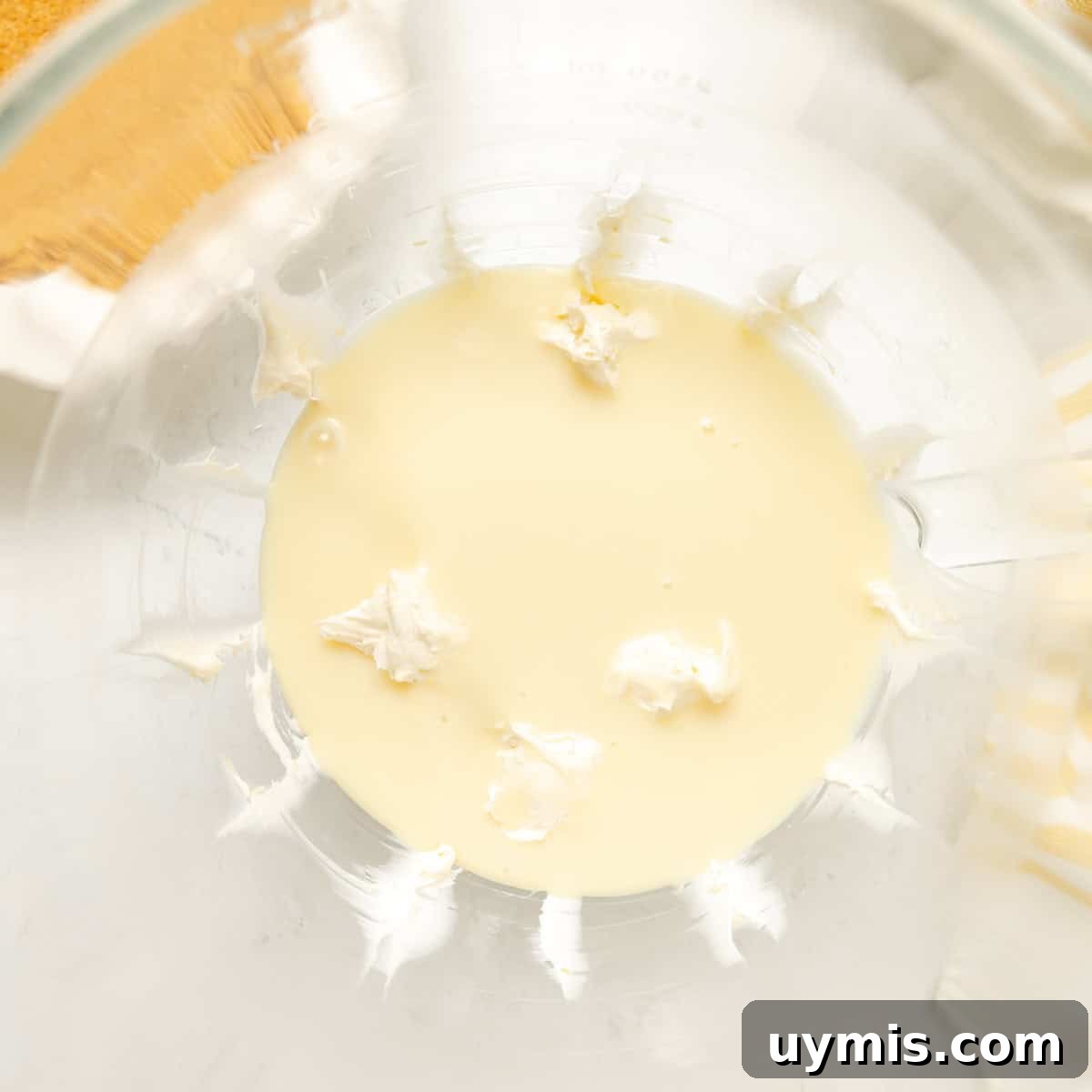 Lemon Icebox Pie Recipe with Creamy No Bake Filling 5 A glass mixing bowl containing a small amount of thick white cream and pale liquid, partially blended together.
